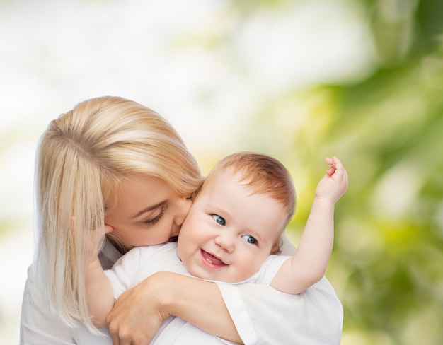 Concept de famille, d'enfant et de parentalité - mère heureuse embrassant un bébé souriant