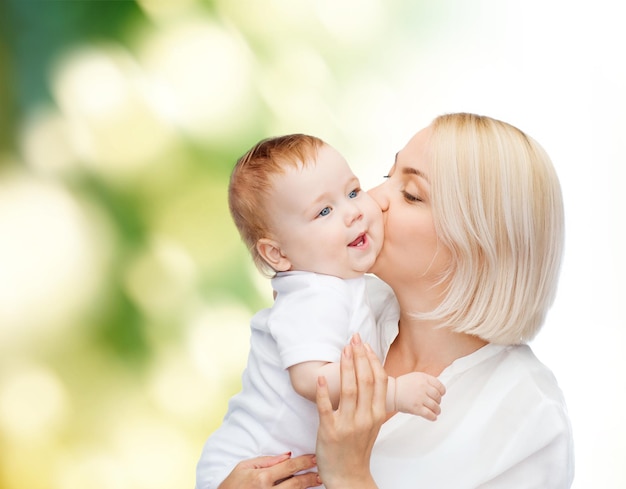 Concept de famille, d'enfant et de parentalité - mère heureuse embrassant un bébé souriant