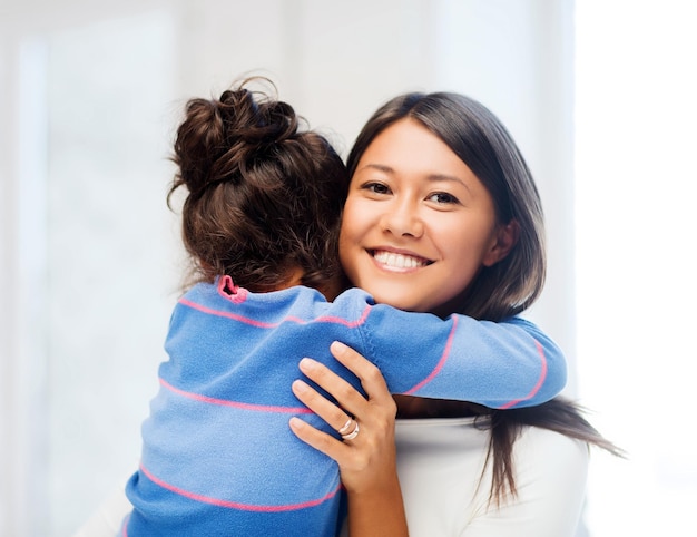 concept de famille, d'enfants et de gens heureux - étreignant la mère et la fille