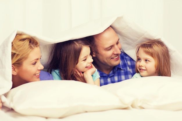 concept famille, enfants et maison - famille heureuse avec deux enfants sous couverture à la maison