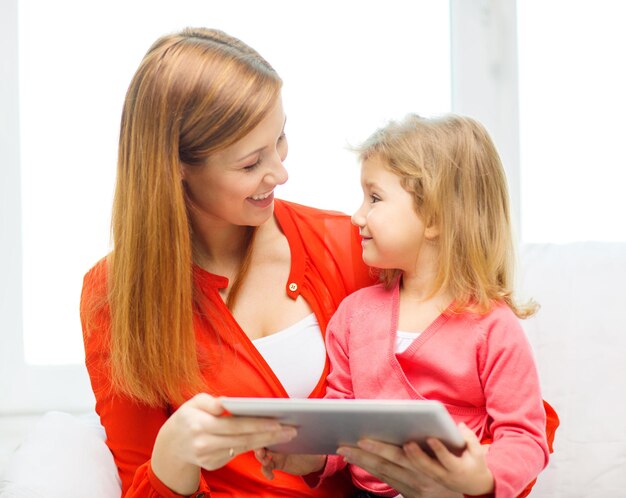 concept de famille, d'enfants, de parentalité, de technologie et d'internet - mère et fille heureuses avec un ordinateur tablette à la maison