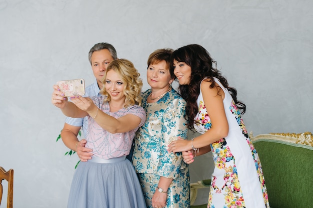 Photo concept de famille, de génération et de personnes - famille heureuse prenant selfie avec les smartphones à la maison