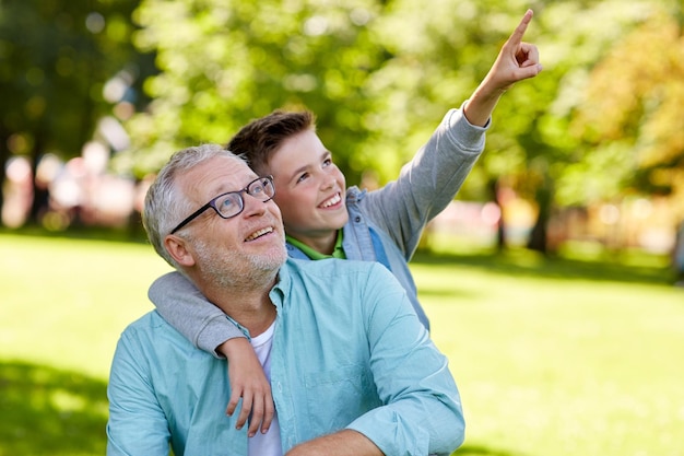 concept de famille, de génération, de relations et de personnes - grand-père et petit-fils heureux pointant du doigt quelque chose au parc d'été