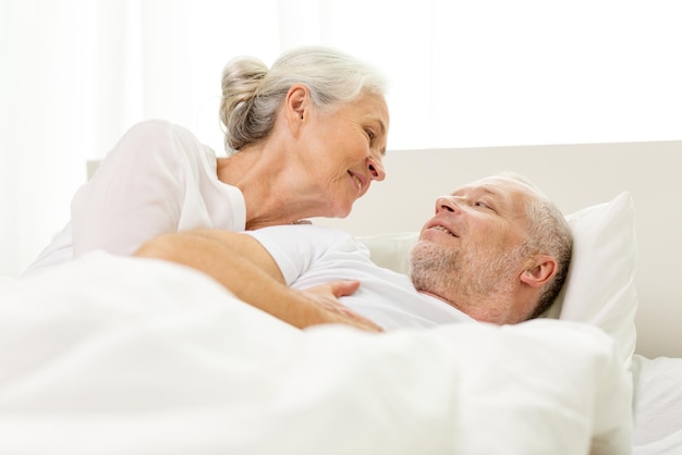 concept de famille, heure du coucher, repos, âge et personnes - coupleur senior heureux couché dans le mauvais à la maison