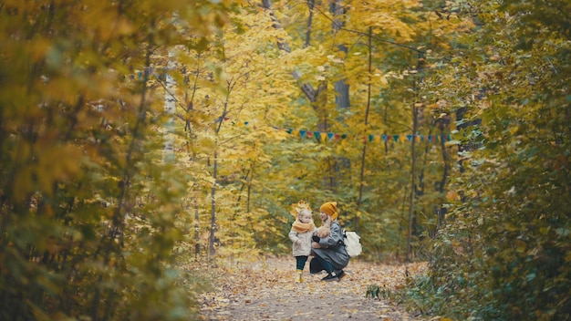 Concept de famille heureuse jolie petite fille avec sa maman se promène dans le parc d'automne