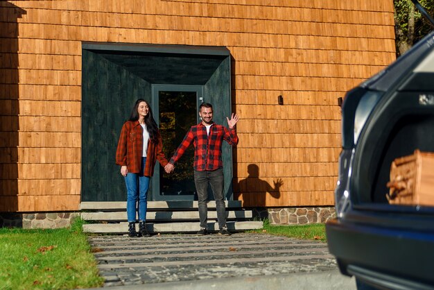 Concept de famille heureuse. Maman et papa sur le porche de la maison leur attendent leurs enfants qui courent.