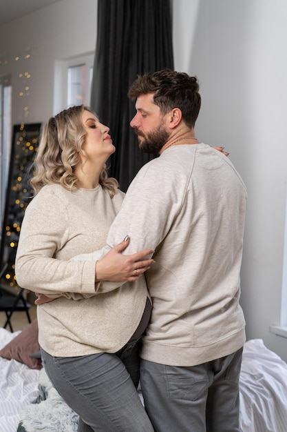 Concept de famille heureuse Mari câlin ventre femme enceinte debout salon intérieur près du canapé Caucasien homme et femme grossesse et nouveau concept de vie Amour et soins