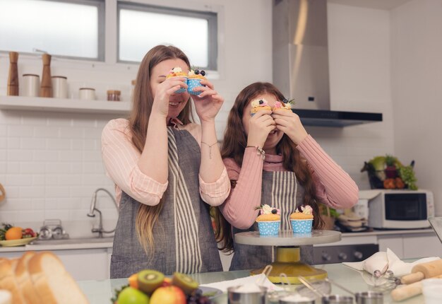 Concept de famille heureuse d'une mère et de sa fille dégustant des cupcakes ensemble dans la cuisine à la maison.