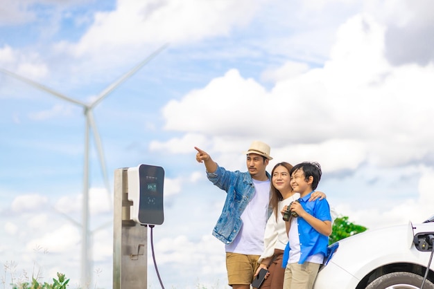 Concept de famille heureuse progressive au parc éolien avec véhicule électrique