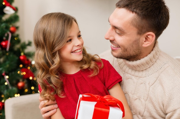 concept de famille, noël, noël, bonheur et personnes - père et fille souriants tenant une boîte-cadeau et se regardant