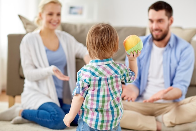 concept de famille et de personnes - petit fils heureux et parents jouant au ballon à la maison