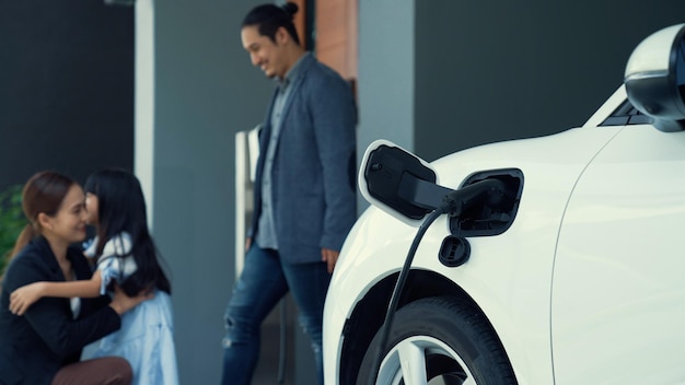 Concept d'une famille progressiste avec une borne de recharge domestique pour un véhicule électrique encourageant un environnement sain et propre Le véhicule électrique alimenté par une technologie d'énergie propre et durable