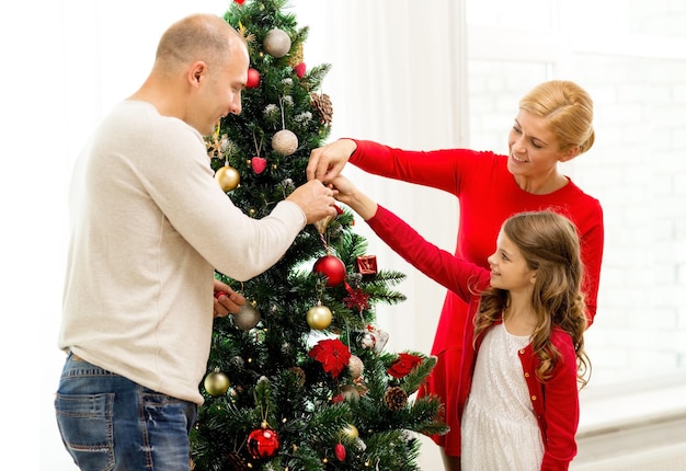 concept de famille, de vacances, de génération et de personnes - famille souriante décorant le sapin de noël à la maison