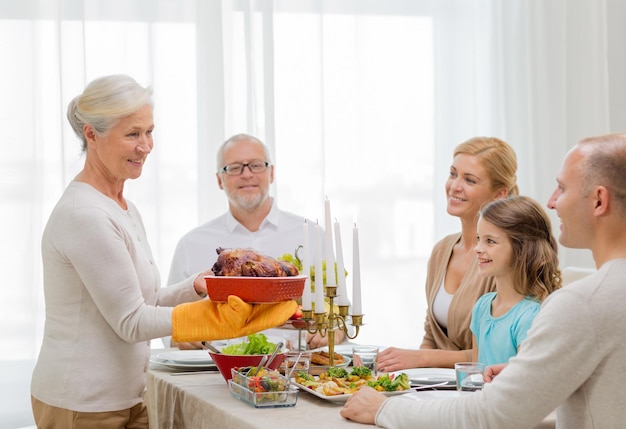 concept de famille, de vacances, de génération et de personnes - famille souriante en train de dîner à la maison