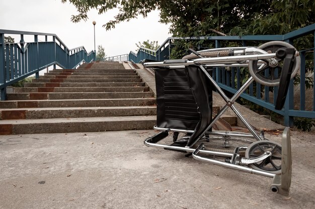 Photo le concept d'un fauteuil roulant dans l'escalier renversé, handicapé, pleine de vie, paralysé. problèmes pour la personne handicapée.