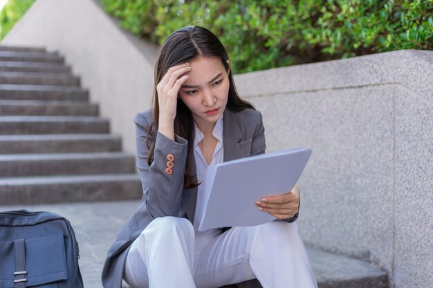 Concept de femme qui travaille une femme assise sur la marche en regardant les demandes d'emploi avec un sentiment d'anxiété et de désespoir.