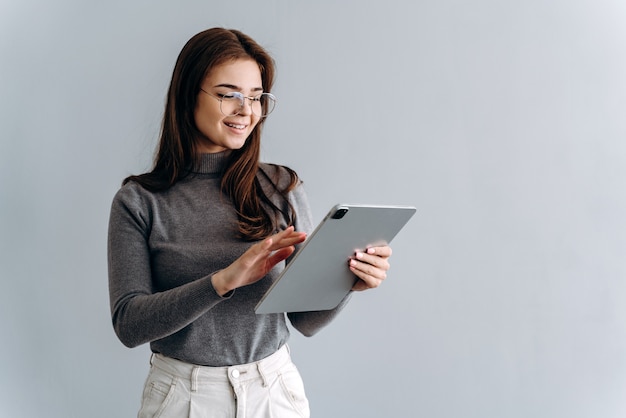 Concept d'une femme avec tablette. Une photo d'une jolie fille souriante sur un gris