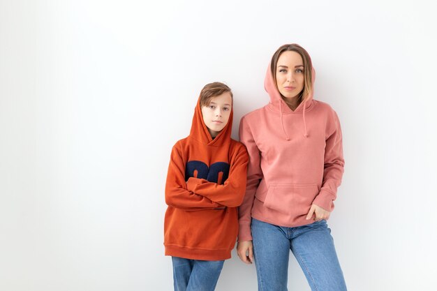 Concept de fête des mères, enfants et famille - garçon adolescent étreignant sa mère sur un mur blanc avec espace copie