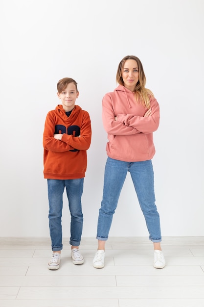 Concept de fête des mères, enfants et famille - garçon adolescent et sa maman posant sur un mur blanc.