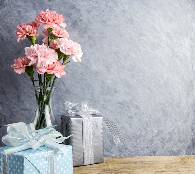 Concept de fête des mères de fleurs d&#39;oeillets roses en bouteille transparente et boîte-cadeau