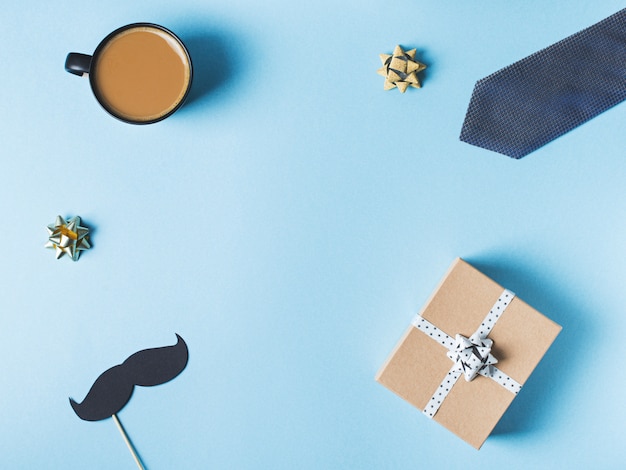 Concept de fête des pères avec boîte-cadeau, cravate et moustache sur fond bleu