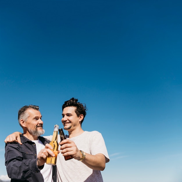 Concept de fête des pères avec père et fils grillage avec de la bière en face de fond de ciel