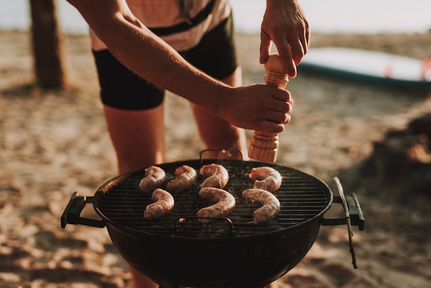 Concept de fête à la plage. Man Grills Saucisses Barbecue.