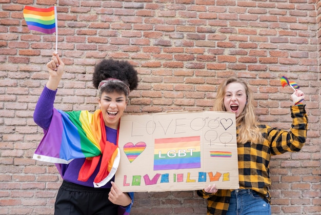 Concept de fierté LGBT. Mode de vie gay. Un vrai couple de lesbiennes qui s'embrasse et s'embrasse avec le symbole emblématique de l'arc-en-ciel.