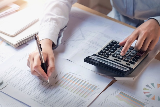 Photo concept finance et comptabilité. femme d'affaires travaillant sur le bureau à l'aide de la calculatrice