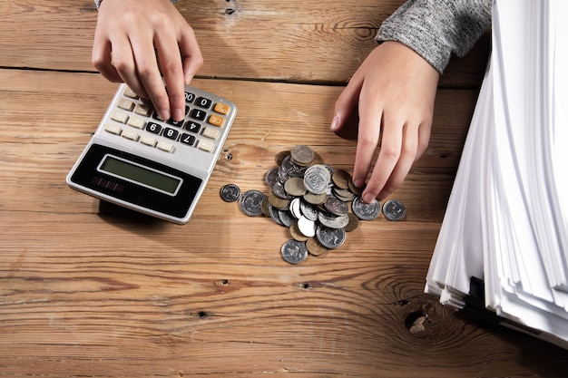 Photo concept financier, femme travaillant dans une calculatrice avec des documents et des pièces de monnaie