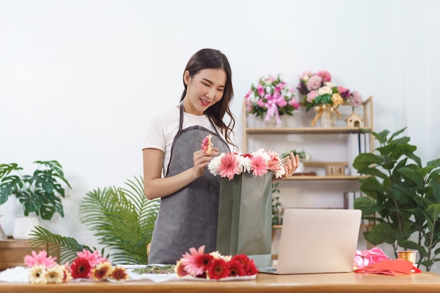 Concept de fleuriste femme fleuriste faisant bouquet de fleurs de chrysanthème et de gerbera dans un sac à provisions