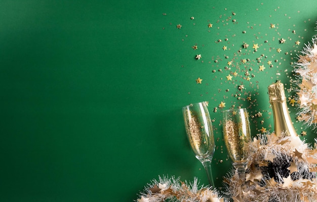 Concept de fond de célébration de bonne année. Champagne avec verre, ruban doré, étoiles et boule de Noël sur fond vert.