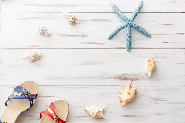 Concept de fond d'été sandales féminines, coquillages, étoiles de mer sur une surface en bois clair