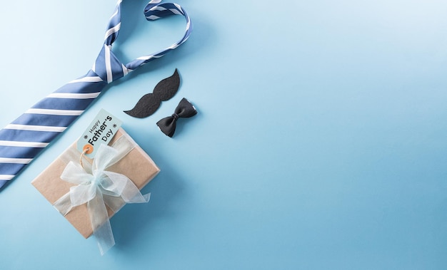 Concept de fond de fête des pères heureux avec boîte-cadeau décoré noeud papillon cravate et moustache sur fond pastel clair