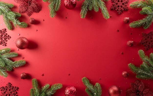 Concept de fond de Noël et du nouvel an. Vue de dessus de la décoration de Noël à base de flocon de neige, boule de Noël et branches de pin sur fond rouge.