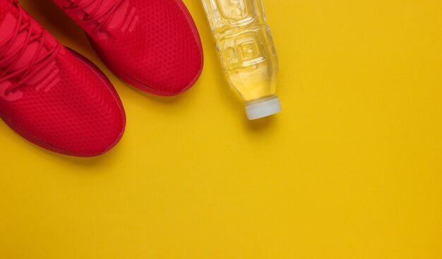 Concept de formation. Chaussures de sport, bouteille d'eau sur fond jaune. Style plat. Copier l'espace