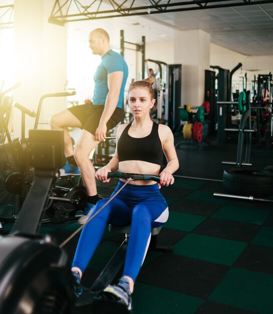 Concept de formation fonctionnelle. Sport homme et femme faisant de l'exercice dans le simulateur de rameur et air bike au gymnase