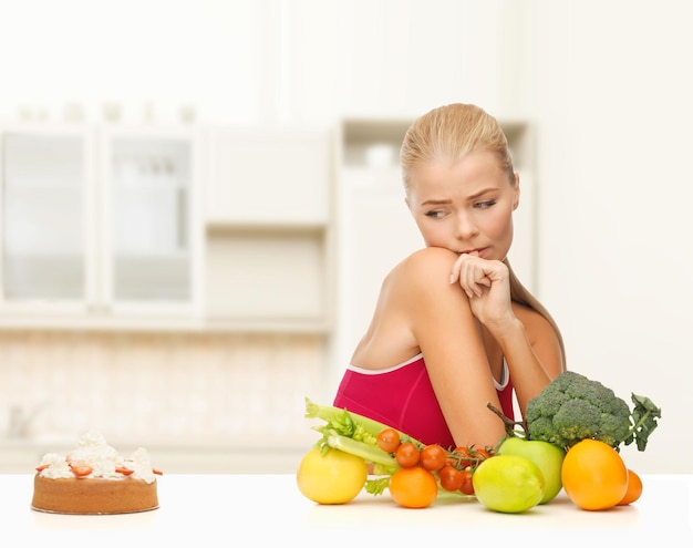 concept de forme physique, de régime, de santé et de nourriture - femme doutante avec des fruits et de la tarte