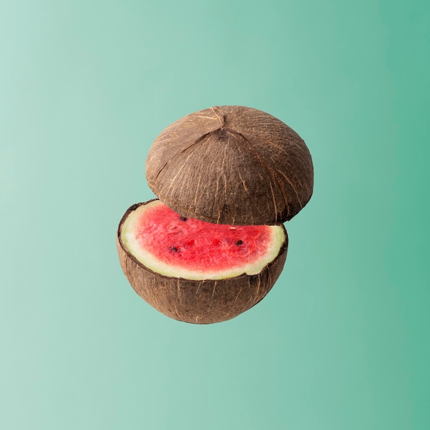 Photo concept de fruit créatif noix de coco coupée en deux avec une pastèque à l'intérieur sur un fond bleu pastel