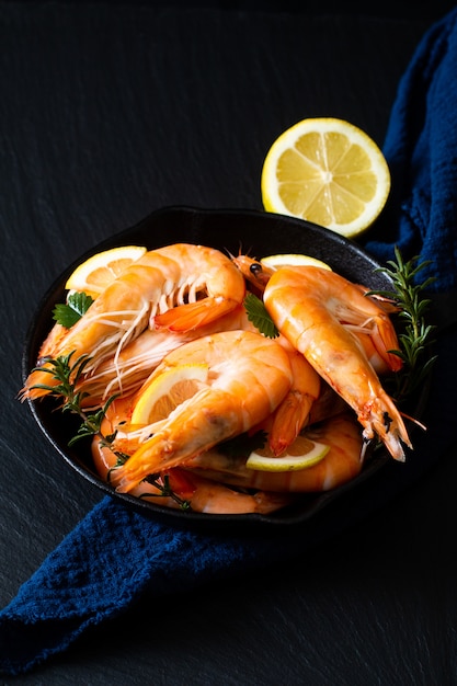 Concept de fruits de mer Ocean King crevettes cuites dans une poêle en fonte sur pierre d'ardoise noire avec des serviettes bleues