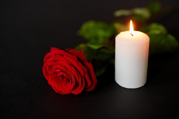 concept de funérailles et de deuil - rose rouge et bougie brûlante sur fond noir