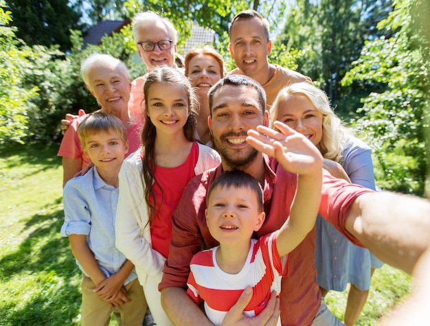 Photo concept de génération et de peuple - famille heureuse prenant un selfie dans le jardin d'été