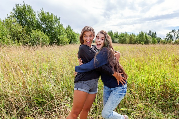 Concept de gens heureux vacances vacances d'été. Groupe de deux amies danser étreindre et s'amuser ensemble dans la nature en plein air. Bons moments meilleur ami.