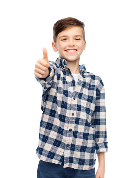 concept de geste, d'enfance, de genre, de mode et de personnes - garçon souriant en chemise à carreaux et jeans montrant les pouces vers le haut