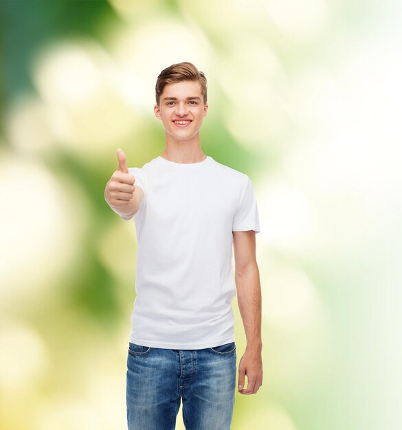 concept de geste, de publicité, d'écologie et de personnes - jeune homme souriant en t-shirt blanc vierge montrant les pouces vers le haut sur fond vert