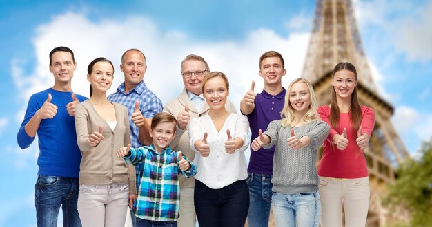 Photo concept de geste, de voyage, de tourisme et de personnes - famille heureuse montrant les pouces vers le haut sur fond de tour eiffel