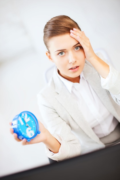 concept de gestion des affaires et du temps - femme d'affaires stressée tenant une horloge