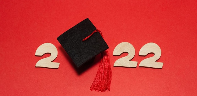 Concept de graduation de l'année 2022 Casquette académique rouge au lieu du numéro 0 en 2022 sur fond rouge Vue de dessus
