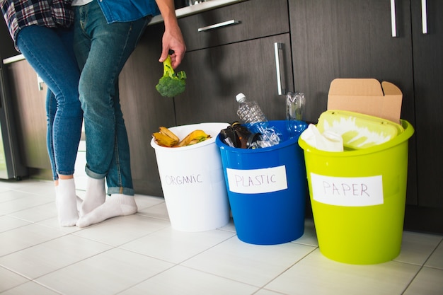 Concept de gros plan. Triez les ordures à la maison. Il existe trois seaux pour différents types de déchets. Une jeune famille trie les déchets dans la cuisine