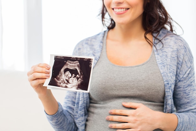 concept de grossesse, de maternité, de personnes et de médecine - gros plan d'une femme enceinte heureuse tenant à l'image échographique à la maison